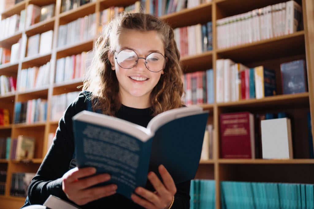 Garota lendo livro em uma biblioteca