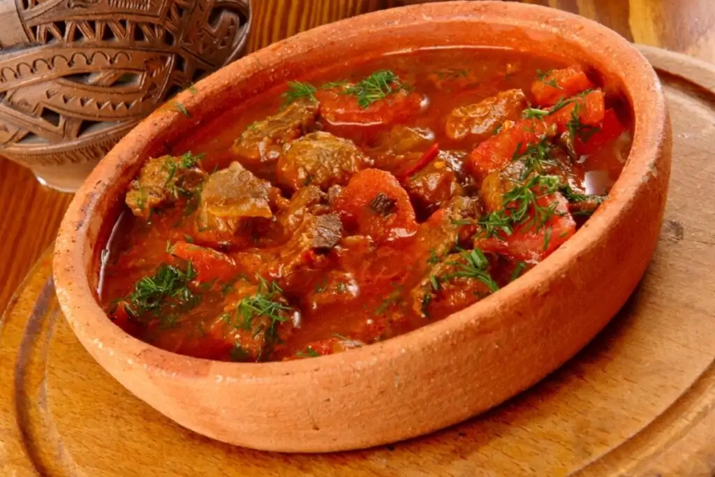 Carne de panela com molho de tomate em travessa em cima de tábua de madeira