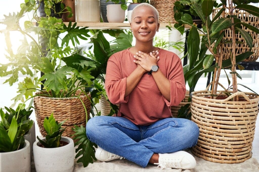 Mulher sentada no chão ao lado de plantas tirando um tempo para respirar