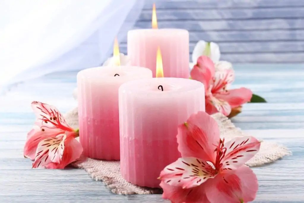 Três velas rosa ao lado de lírios rosa 