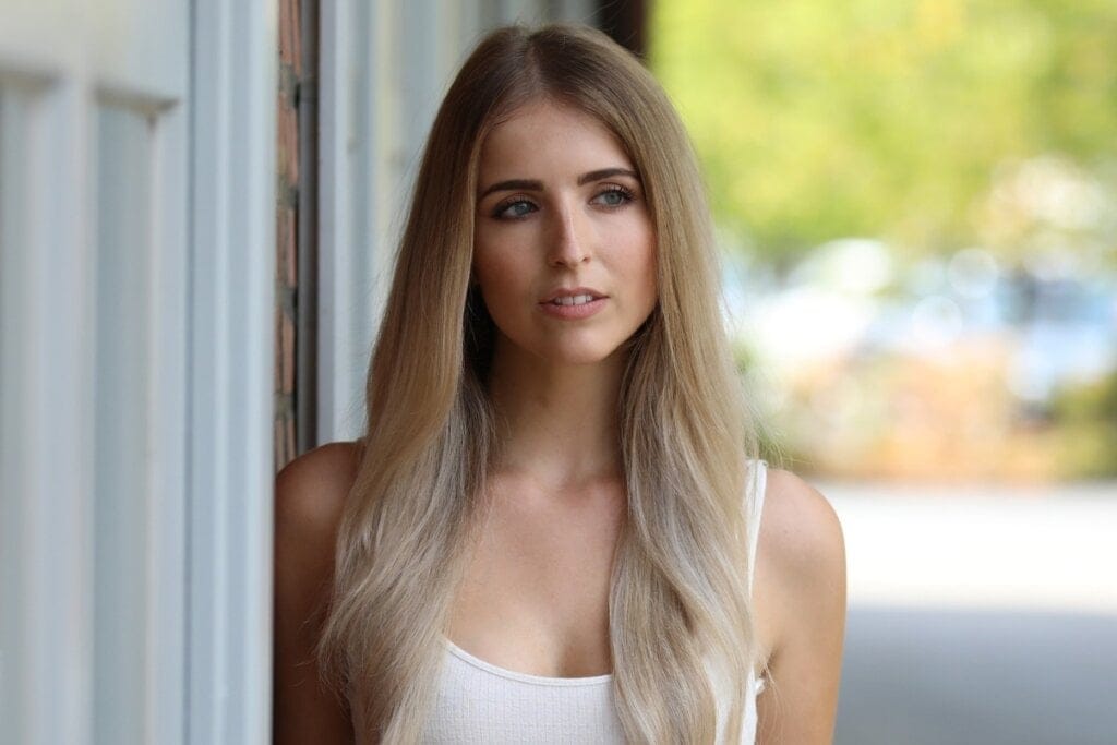 Mulher com cabelo loiro levemente bege posando para foto na rua