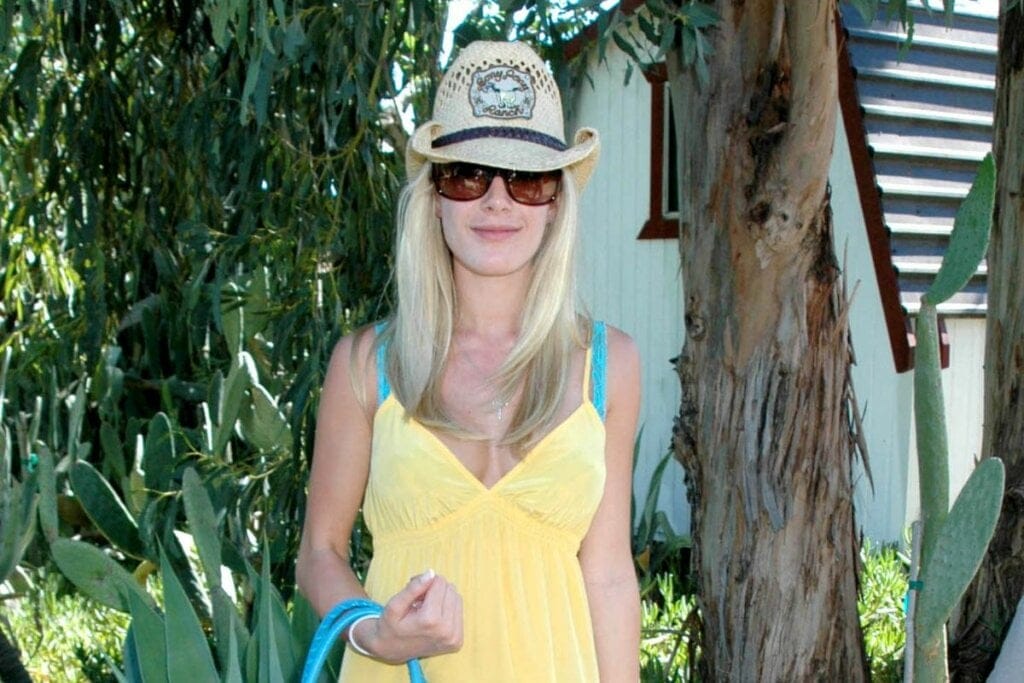 Mulher usando um vestido amarelo e chapéu de palha cowboy posando para foto