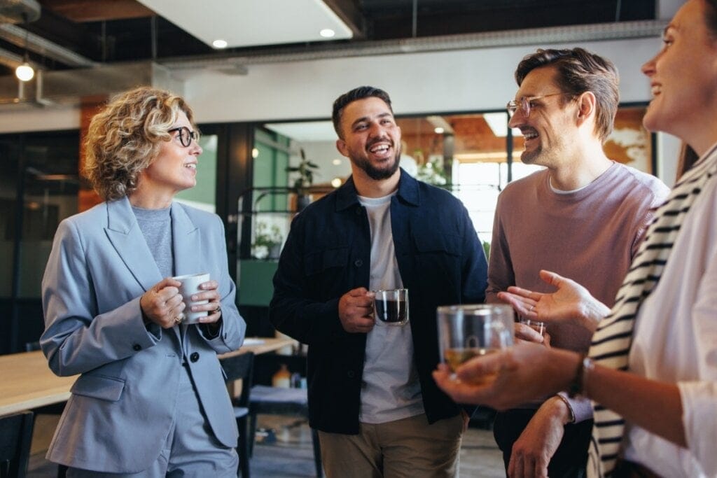 Homens e mulher reunidos em um escritório segurando uma xícara de café