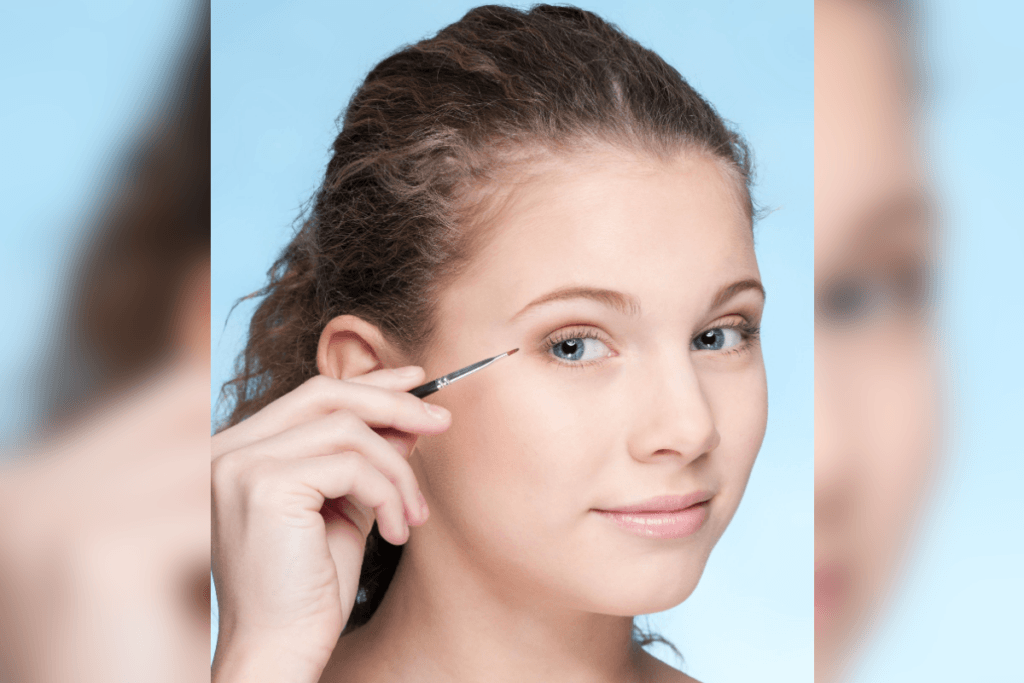 Mulher de olhos azuis em fundo azul segurando um pincel fino