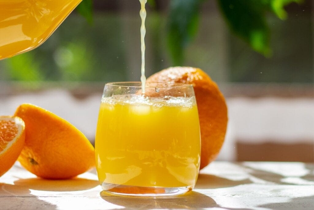 Copo de vidro com suco de laranja e pedras de gelo