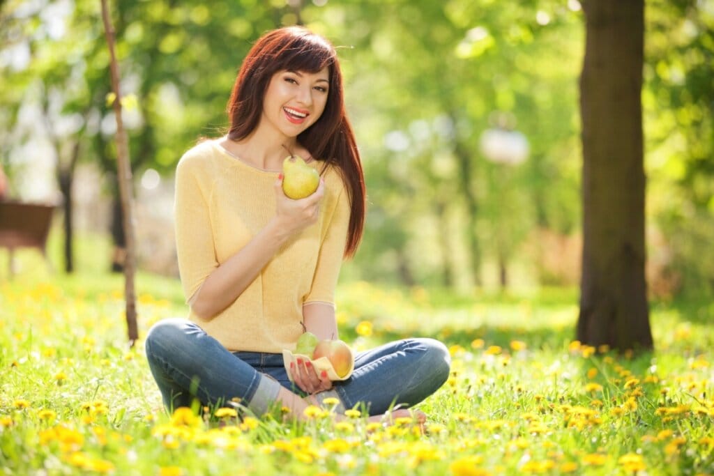 Mulher comendo pera no parque