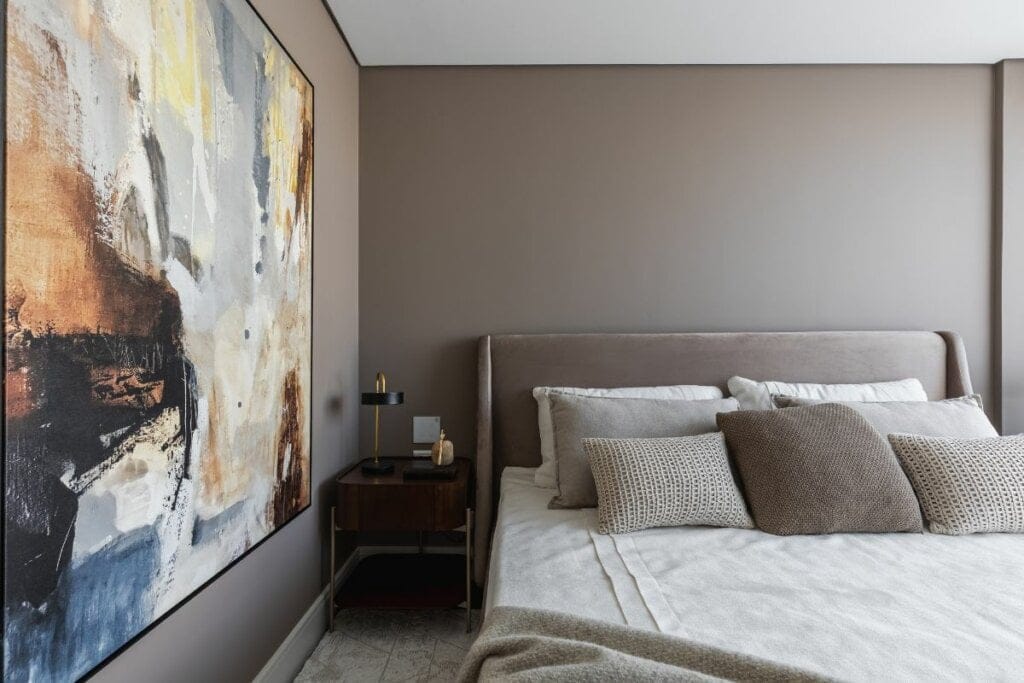 Quarto com parede bege com uma cama com encosto de cama da mesma cor na frente