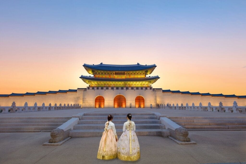 Imagem do Palácio Gyeongbokgung iluminado por luzes amarelas no entardecer 