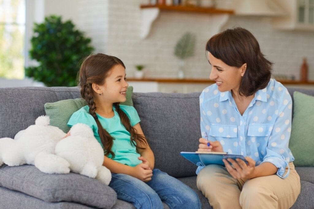 Menina e mulher sentadas em um sofá conversando