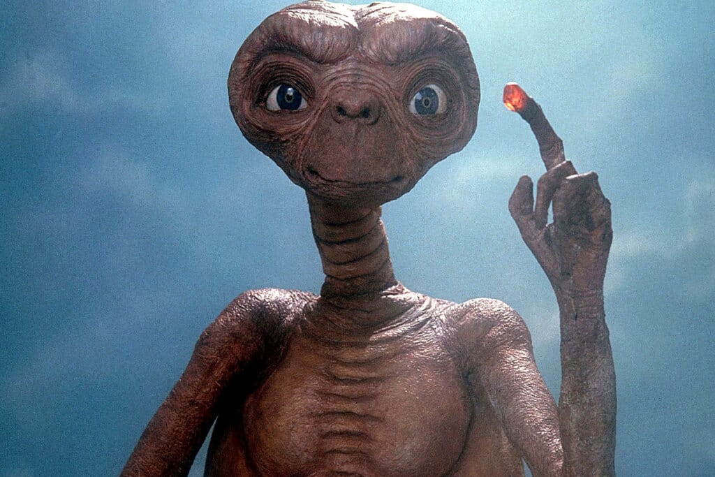imagem de e.t. do filme marrom, apontando para cima e em fundo azul