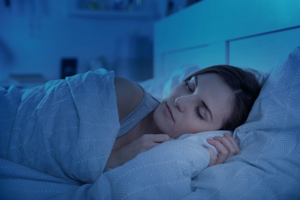 Mulher dormindo em cama com travesseiro e cobertor