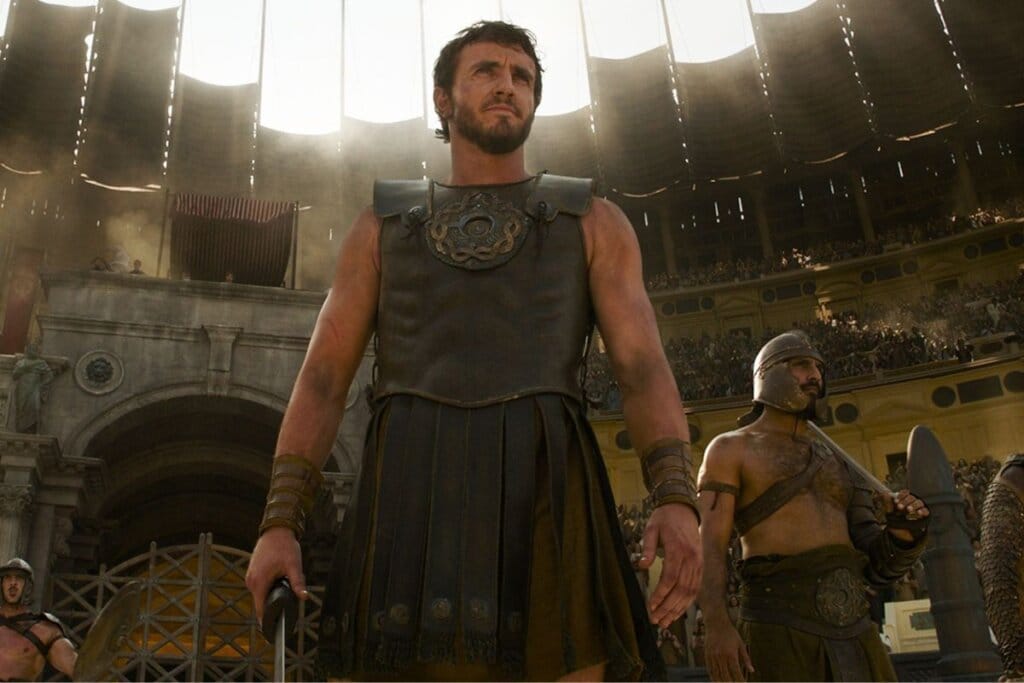 Protagonista do filme Gladiador II em pé dentro do Coliseu usando armadura e segurando uma espada 