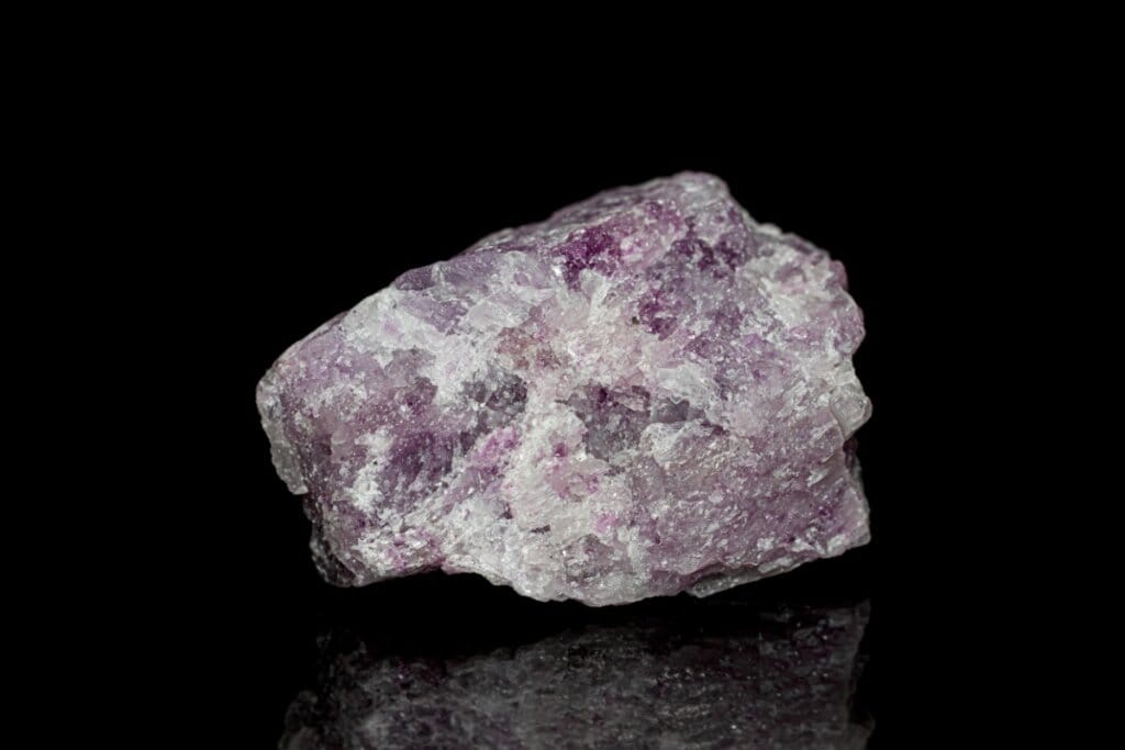 Pedra lepidolita em tons de roxo e branco em fundo preto