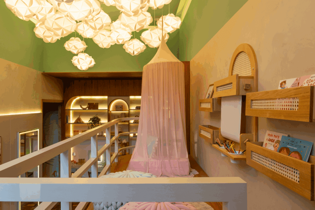 Mezanino em madeira com local de desenho e leitura, com uma cortina rosa cobrindo um puff rosa