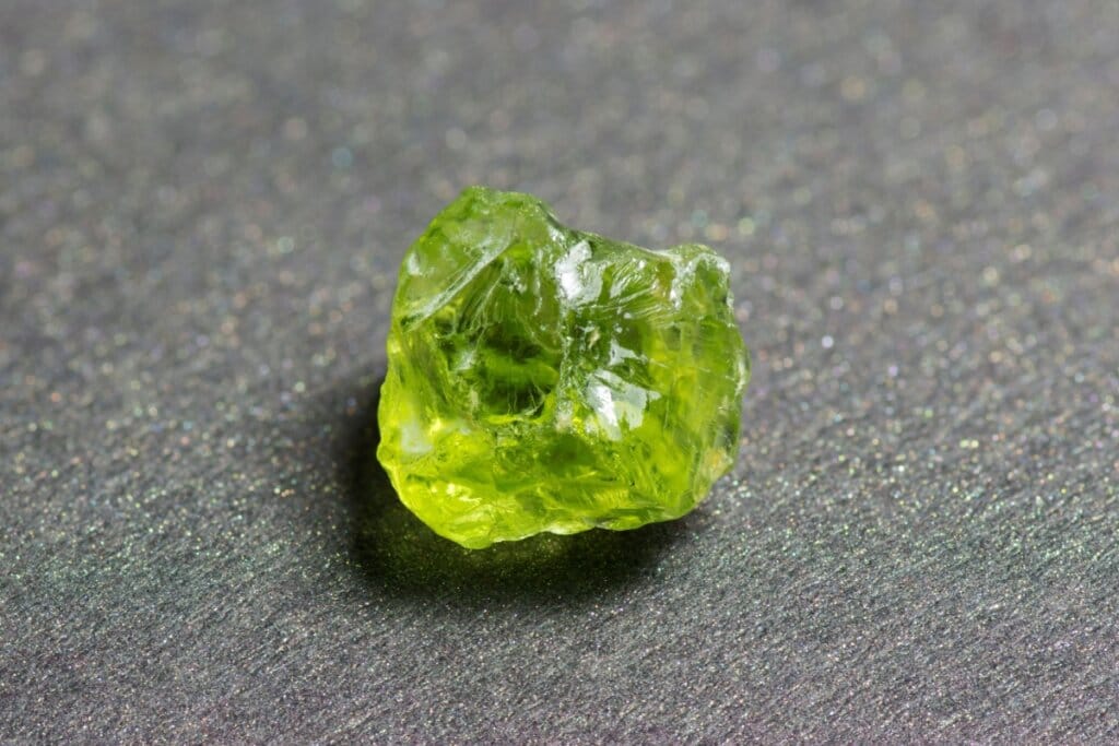 Cristal peridoto verde em cima de mesa cinza