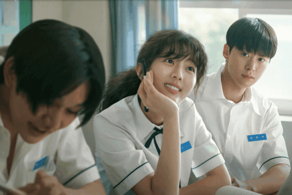 Cena do filme "Amor Enrolado" com três jovens de uniforme escolar e a protagonista sorrindo