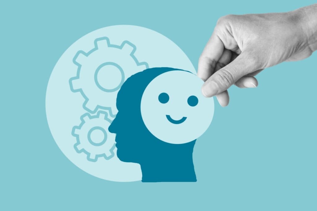 Ilustração em azul de engrenagens ao lado de uma cabeça e uma mão segurando um desenho de um rosto sorrindo