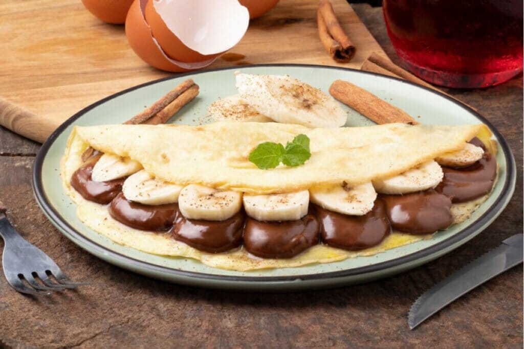 Crepioca recheada com banana e chocolate em cima de um prato verde