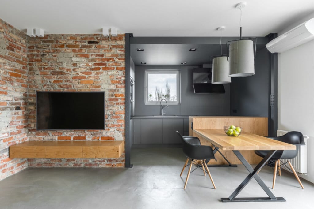 Casa com parede com tijolos aparentes com TV e mesa 