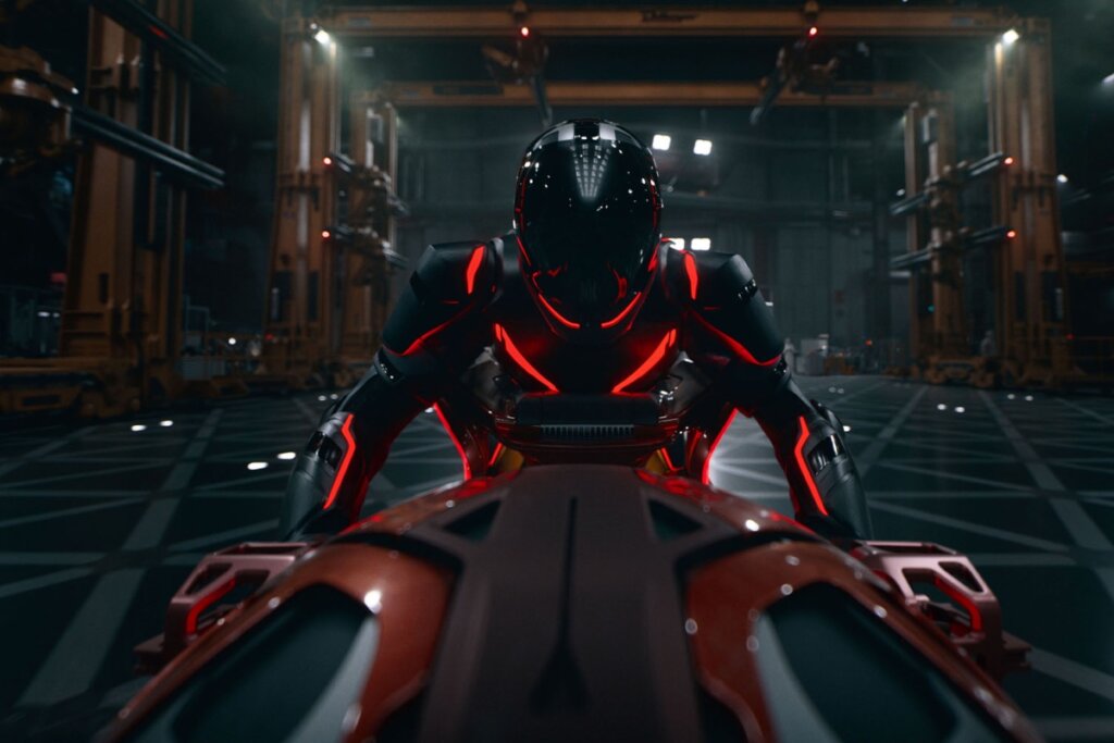 Cena de "Tron: Ares", mostrando personagem em armadura tecnológica iluminada em vermelho