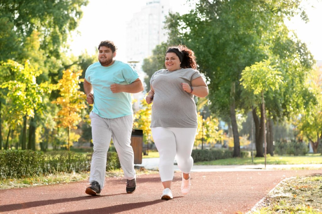 Homem e mulher acima do peso correndo em um parque