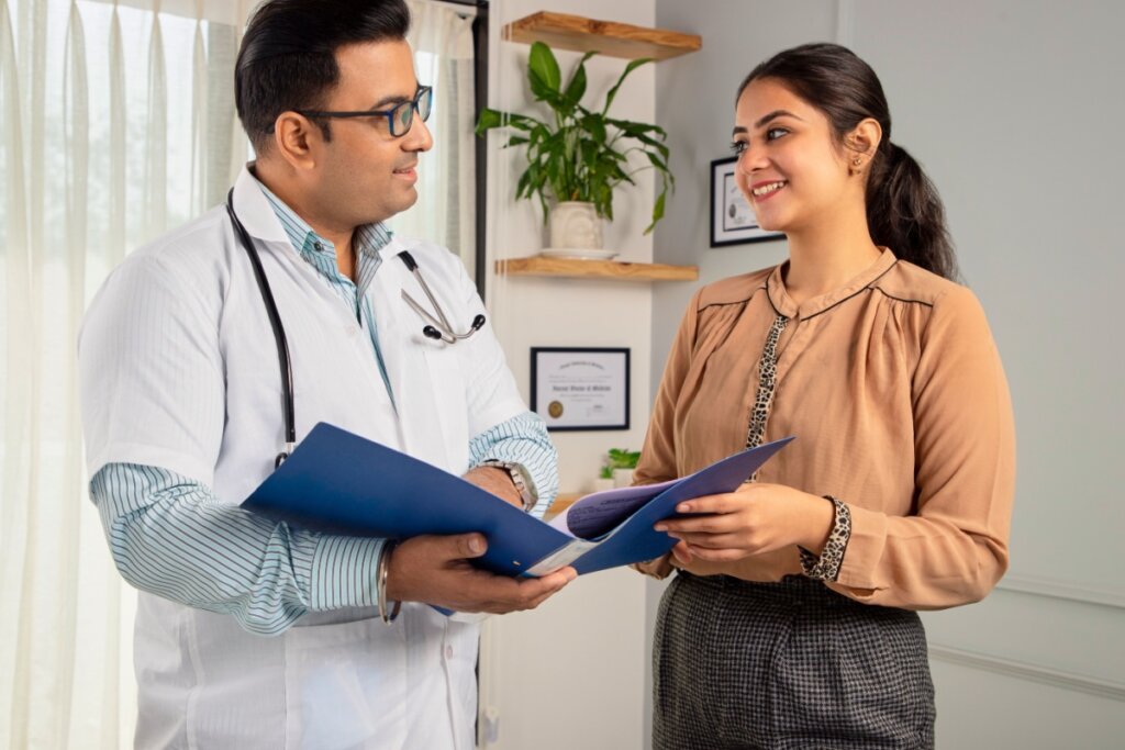 Médico e mulher em pé conversando e segurando pastas azuis
