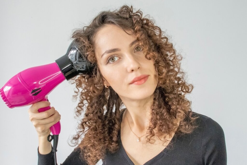 Mulher com cabelos cacheados usando difusor neles