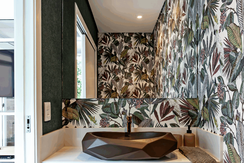 Lavabo com parede com papel de parede com folhas e flores e pia preta 