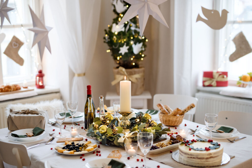 Uma mesa posta para o jantar de Ano-Novo com taças, pratos, velas, comidas, plantas