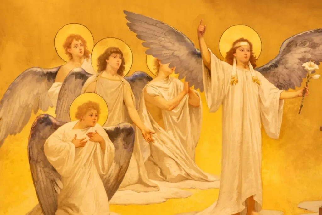 Imagem do arcanjo São Gabriel com roupa branca e asas azuis, segurando flor, com outros anjos menores atrás dele