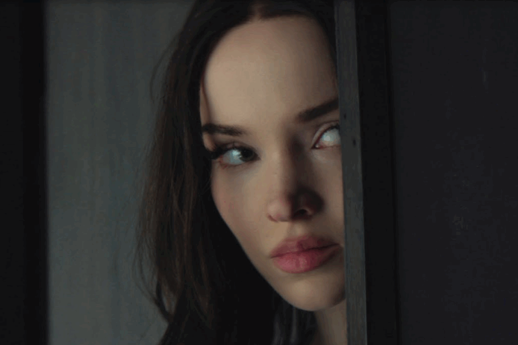 Mulher observando o ambiente por uma fresta de porta em cena de suspense da série 56 Dias