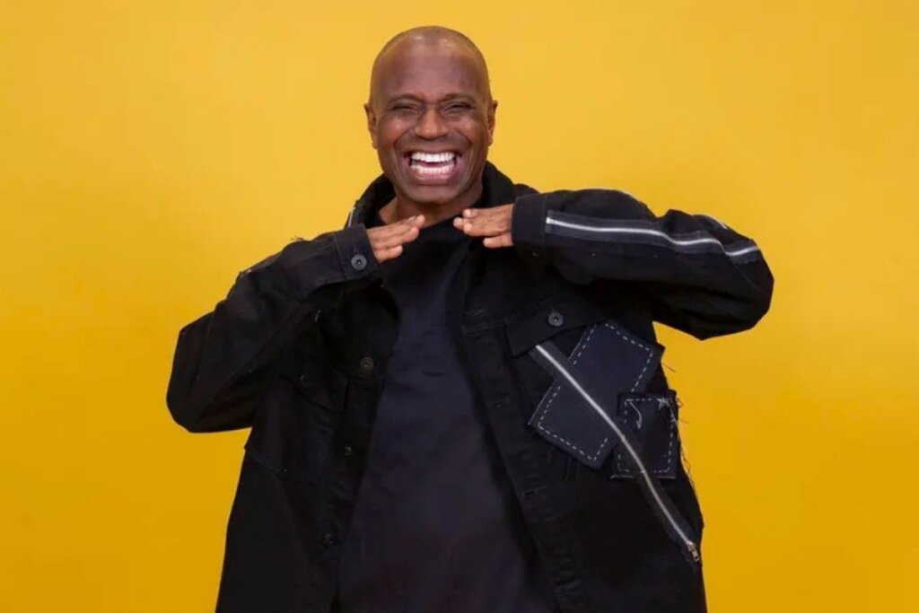 Edílson Capetinha posando para foto em frente a um fundo amarelo 