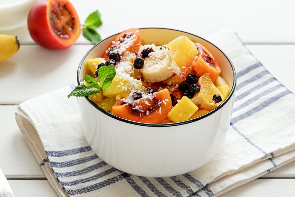 Recipiente branco com salada de frutas com tamarilho e mirtilo