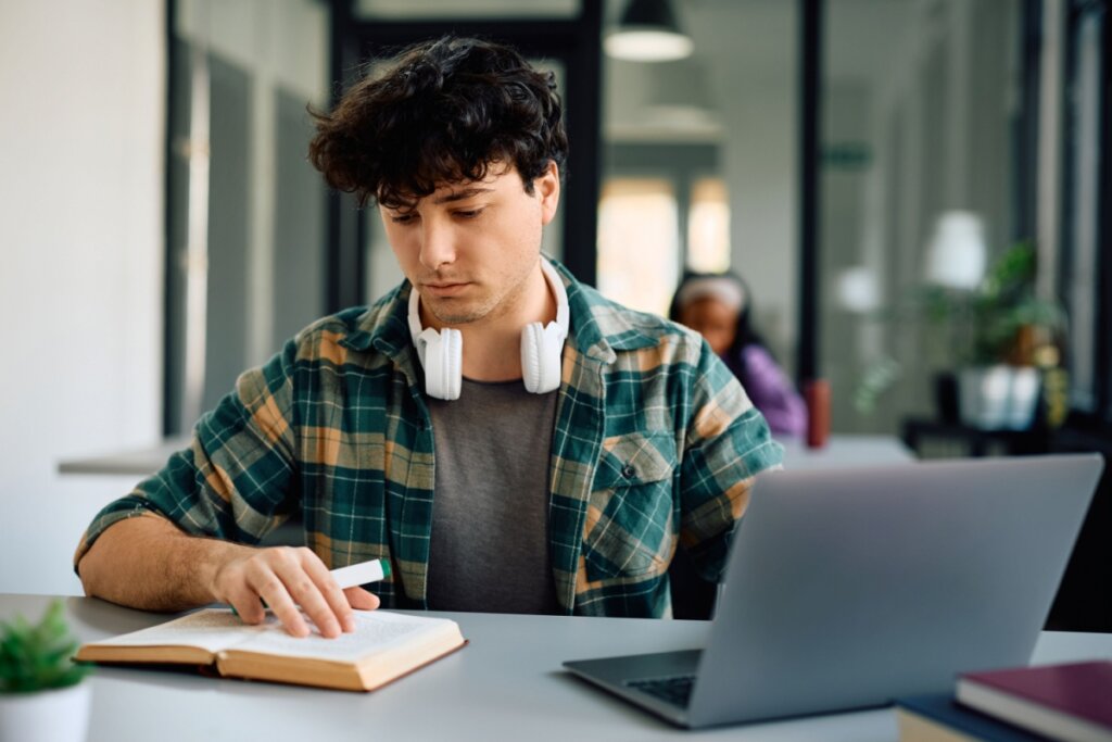 Jovem sentado em frente a um notebook estudando