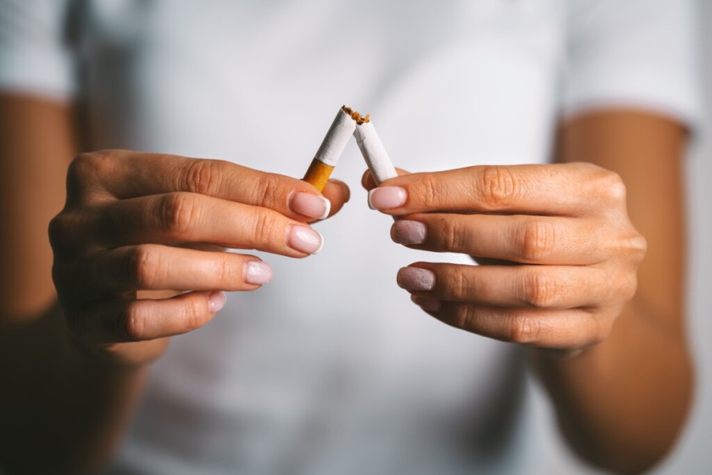 Mãos de uma mulher quebrando um cigarro ao meio