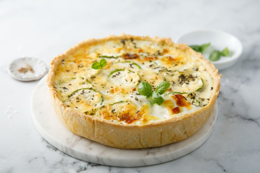 Quiche de abobrinha servido em cima de mesa de mármore branca