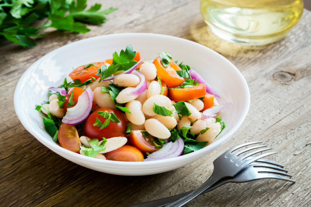 Salada de feijão-branco com tomate e salsa em um prato branco 