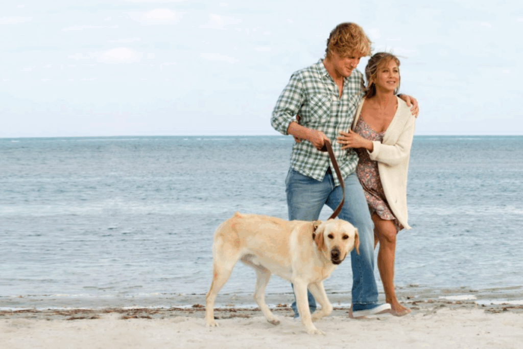 Owen Wilson e Jennifer Aniston passeando na praia com o labrador Marley em cena do filme "Marley & Eu"