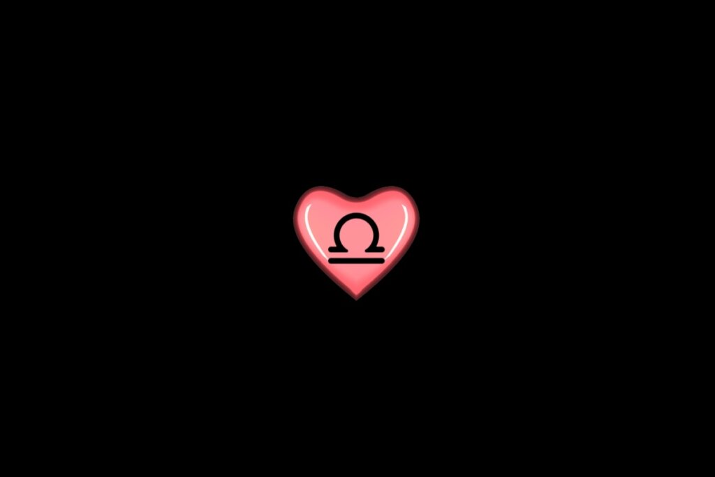 Ilustração de um coração rosa, com o símbolo do signo de libra dentro, centralizado em um fundo preto