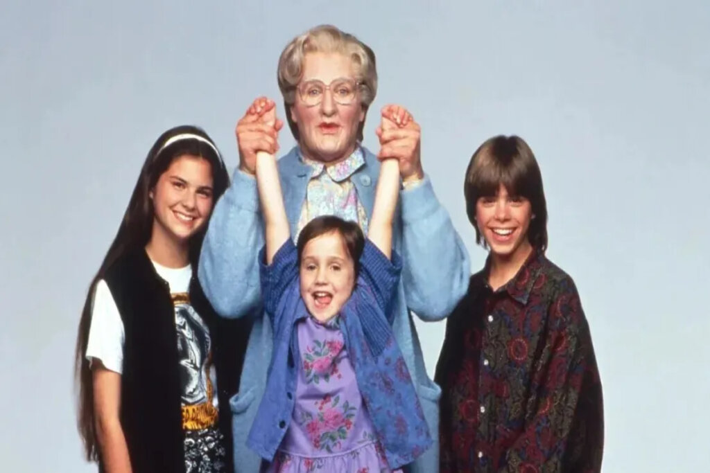 A imagem mostra os personagens principais do filme Uma Babá Quase Perfeita. No centro aparece a babá Sra. Doubtfire, interpretada por uma pessoa caracterizada como uma senhora idosa, ao lado de três crianças sorridentes.