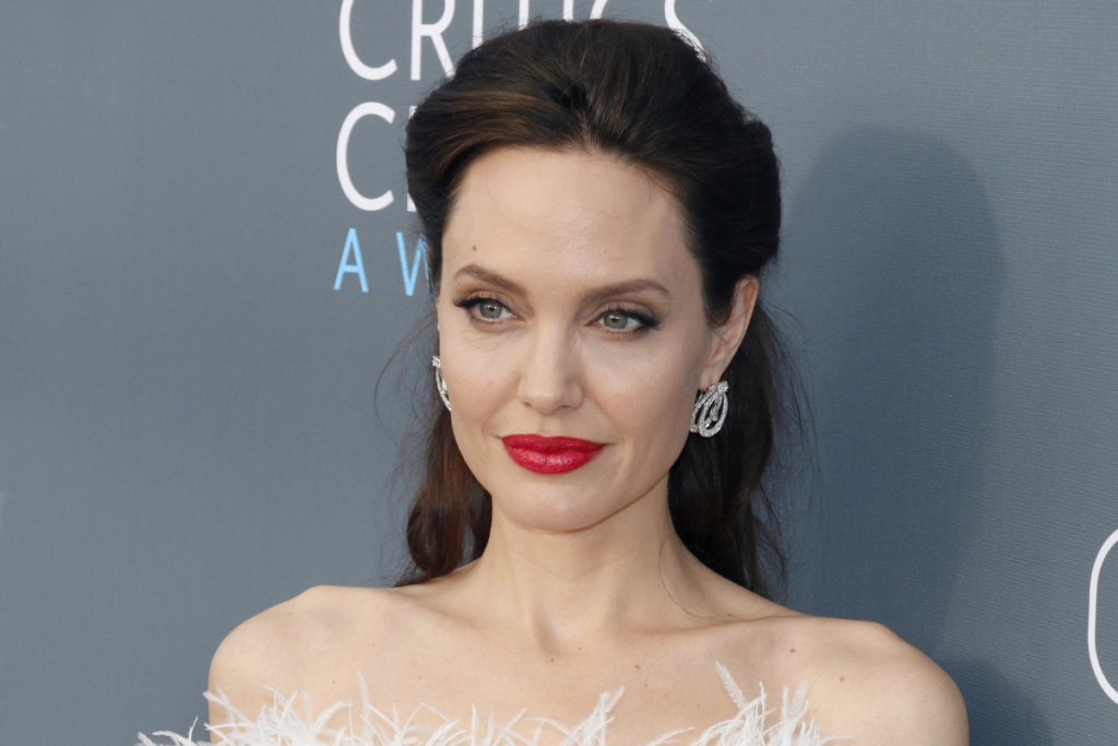 Angelina Jolie com cabelo preto e batom vermelho posando para foto