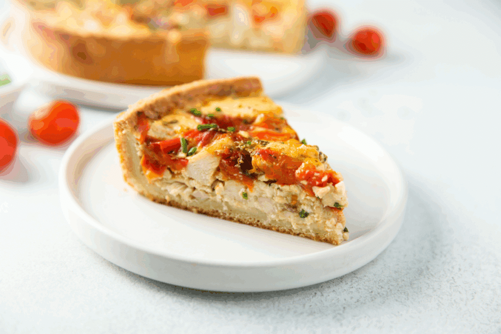 Pedaço de quiche de frango com tomate seco em um prato branco 