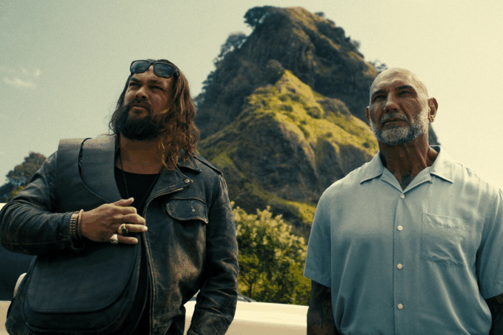 Protagonistas de "Dupla Perigosa", em pé e olhando para cima. Ao fundo, uma montanha com raios de sol