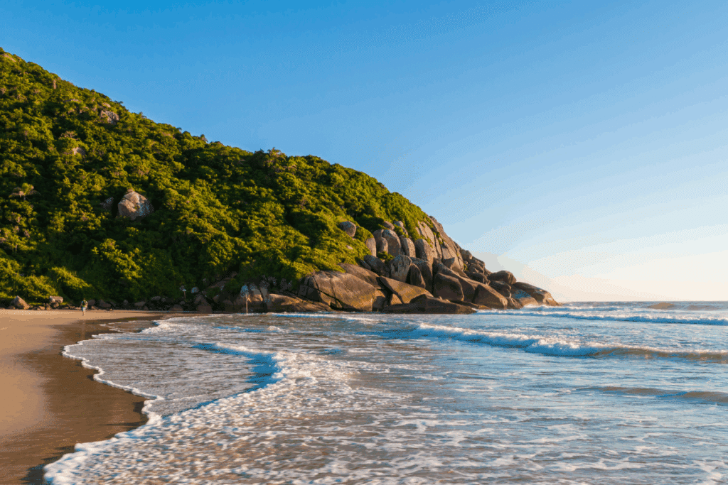 Imagem de praia com montanha ao fundo no fim da tarde